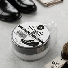 Bright instant shine shoes sponge on a concrete surface with black shoes and a brush.